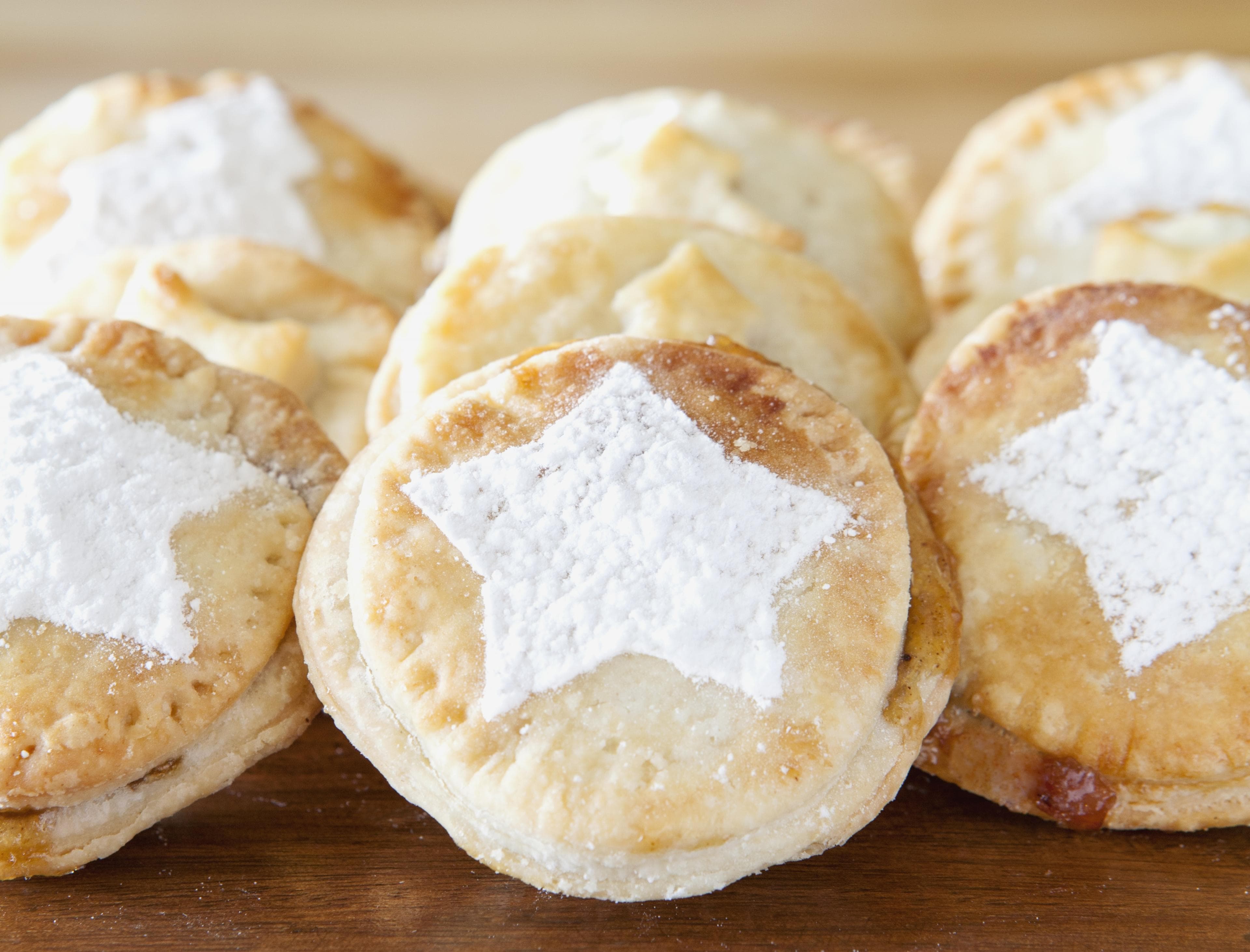 six mince pies are displayed with a white star sprinkled on each