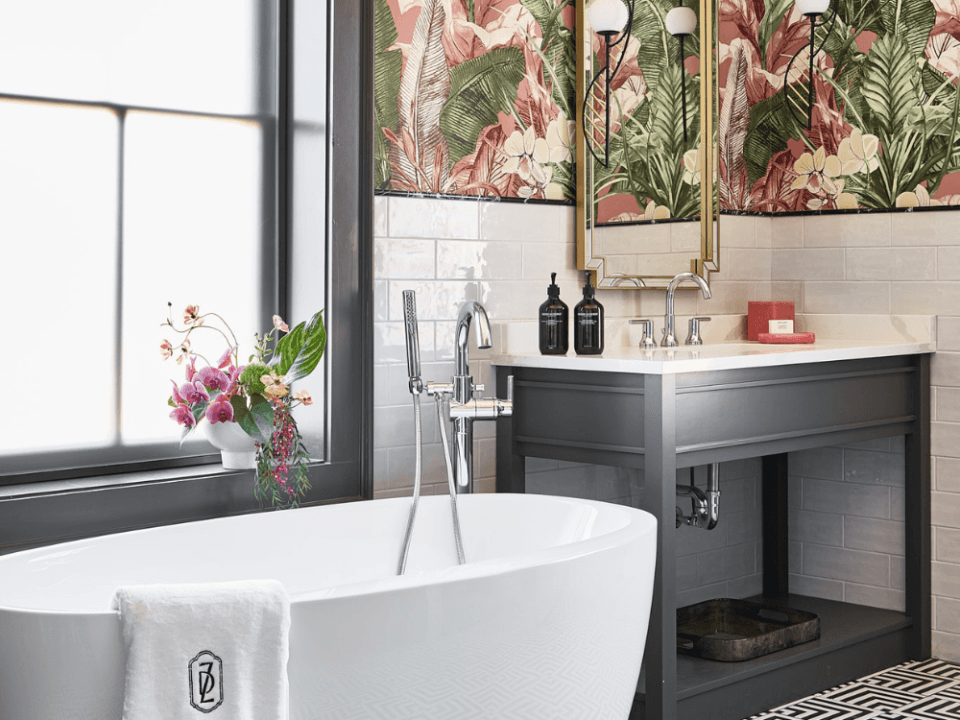 white tiled and tropical wallpapered bathroom with a soaking bathtub and black and white sink white tiled and tropical wallpapered bathroom with a soaking bathtub and black and white sink