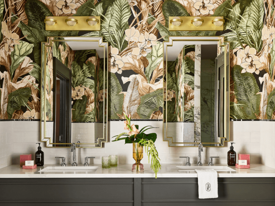 green tropical wallpaper bathroom with two large gold mirrors and a white and black double sink countertop green tropical wallpaper bathroom with two large gold mirrors and a white and black double sink countertop