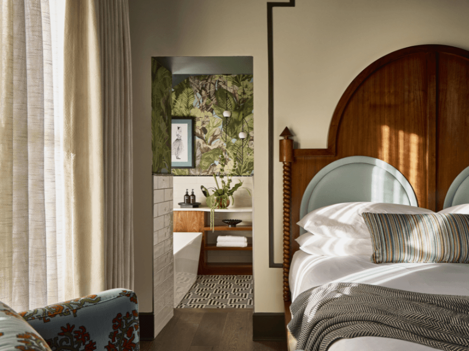 wood headboard bed and doorway leading into tropical green wallpaper bathroom wood headboard bed and doorway leading into tropical green wallpaper bathroom
